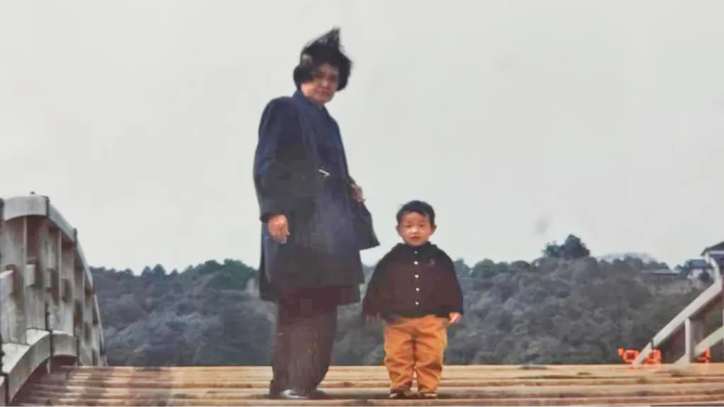 桟橋に立つ喪服姿の女性と幼い子どもの古い写真
